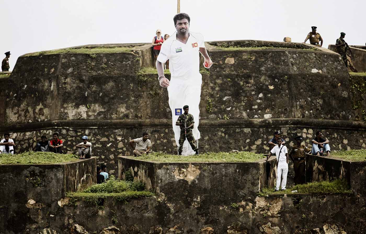 Fans and security men on the ramparts of the Galle Fort in front of a giant cutout of Muttiah Muralitharan