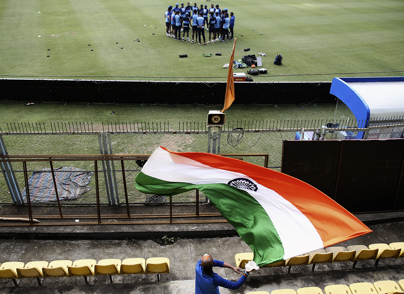 Sudhir Gautam waves an India flag while India players get into a huddle