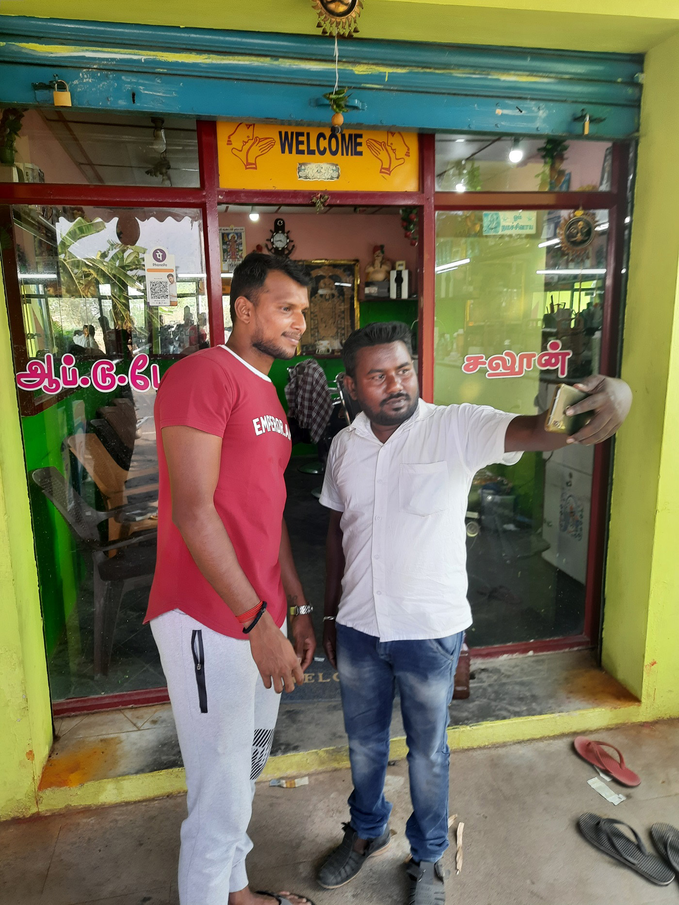 Home-town hero: Natarajan poses for a selfie with a fan outside the Up to Date hair salon, one of his childhood haunts