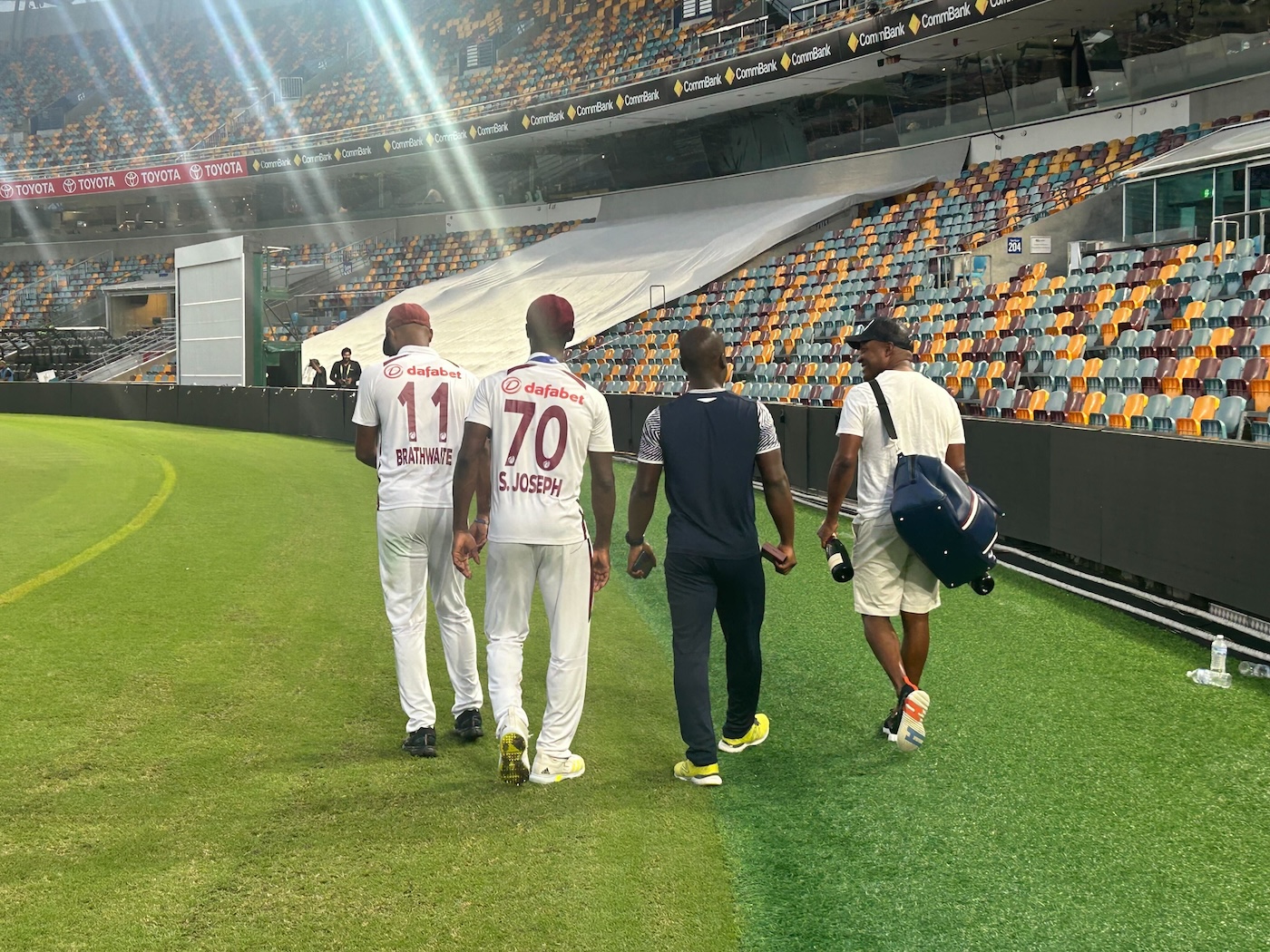 Brian Lara, champagne in hand, accompanies Joseph and Brathwaite to the dressing room after the Brisbane win