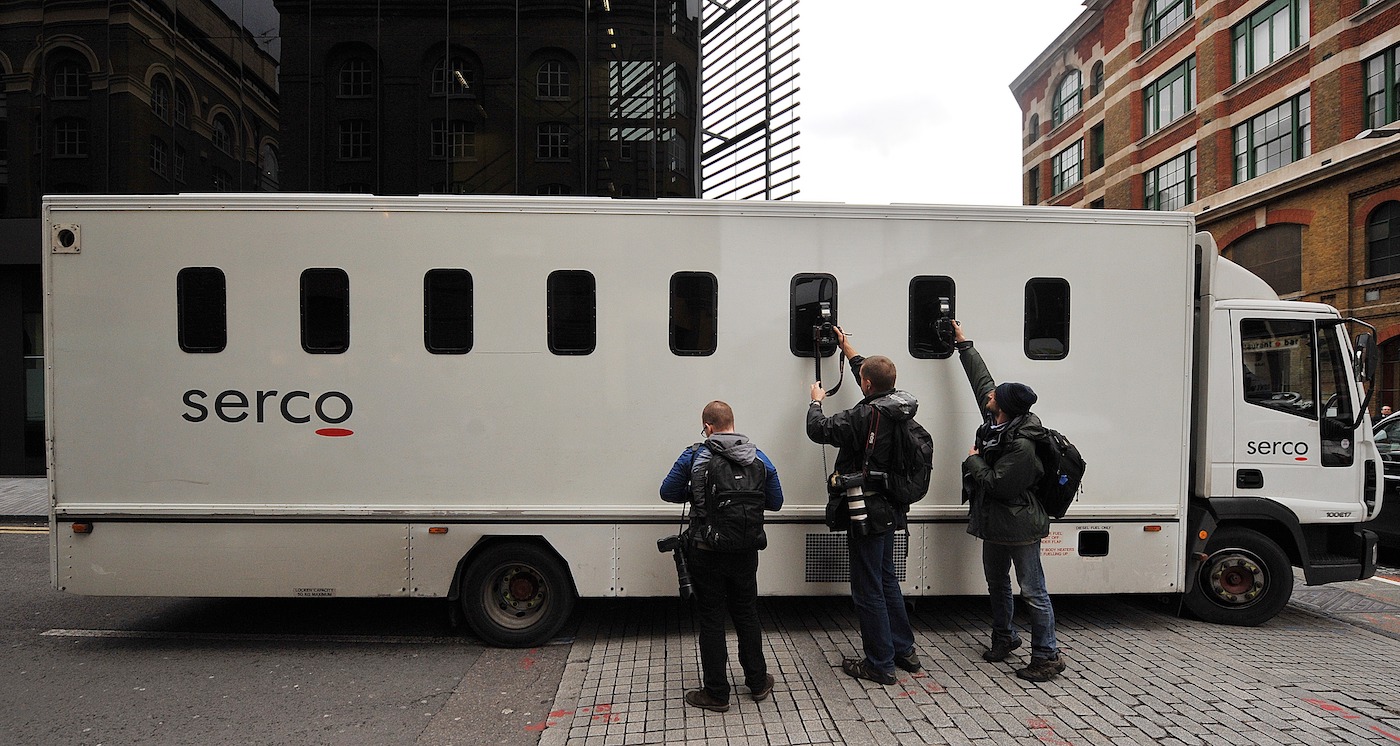 Photographers take pictures through the window of a prison van as it leaves Southwark Crown Court