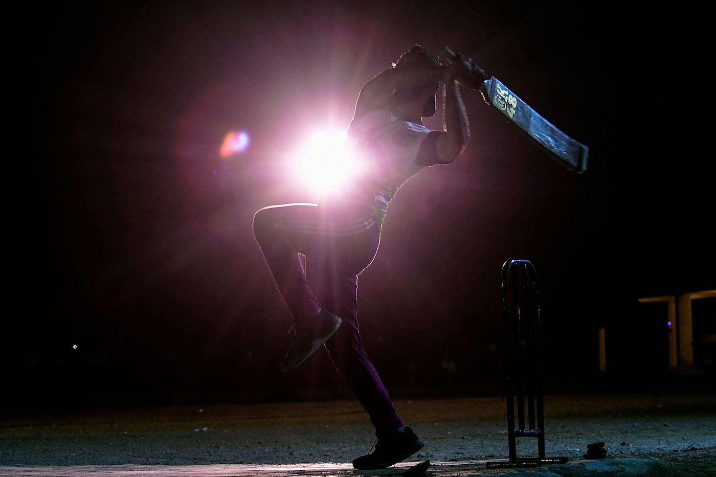 Shine on: a tape-ball player on the streets of Karachi strikes a dramatic pose
